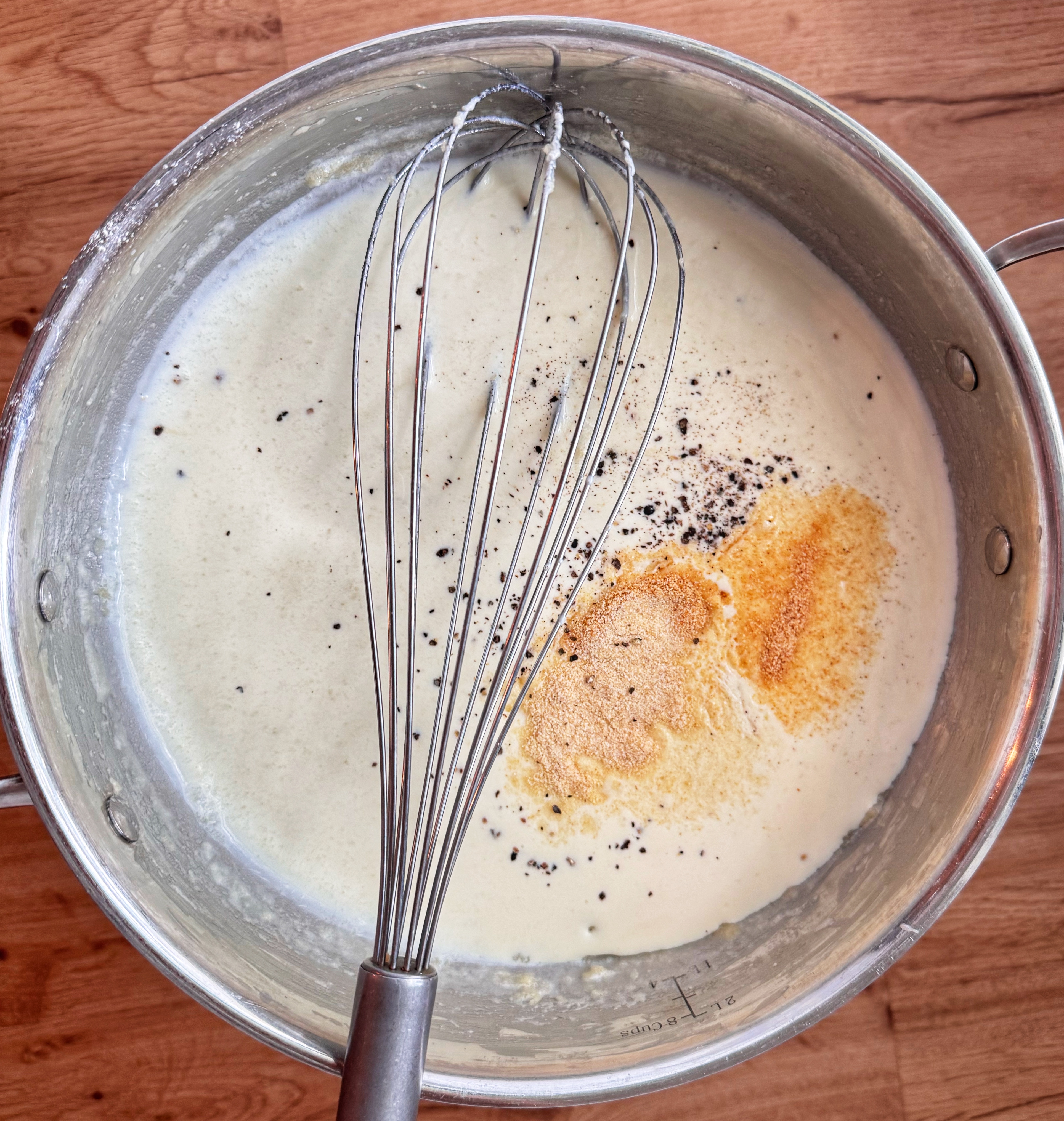 spices on top of sauce with whisk and pan