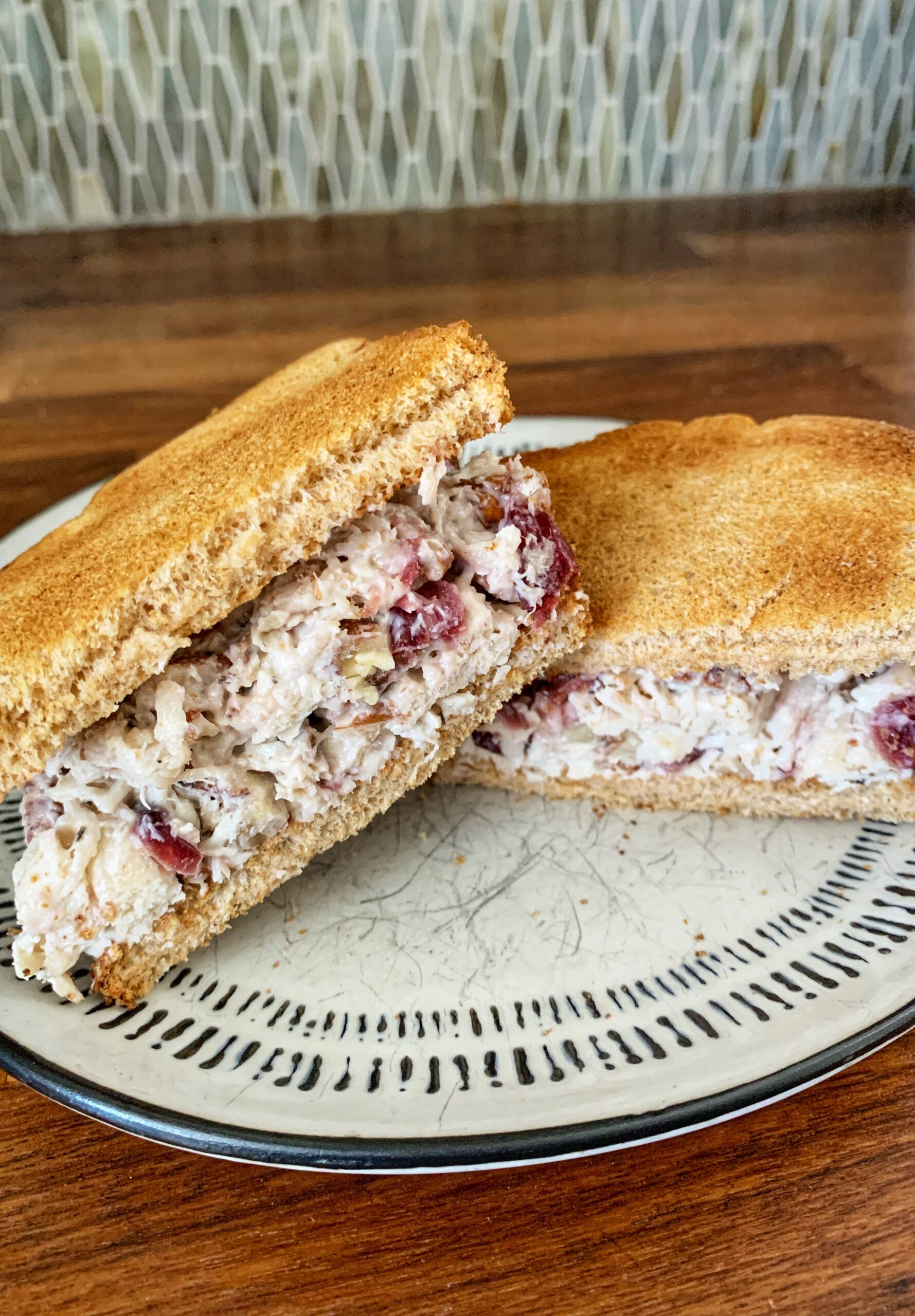 Chicken salad sandwich sliced in half stacked on plate